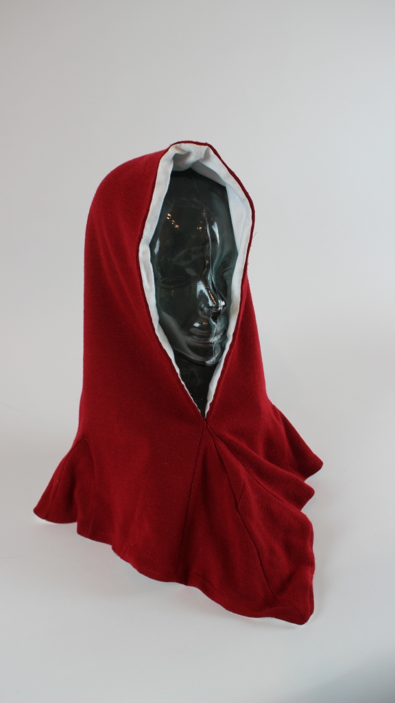 Red medieval style hood with a white lining on a glass mannequin head